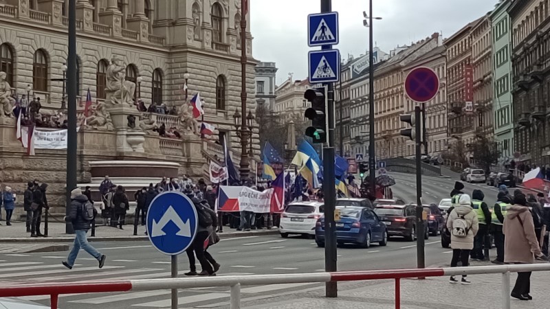 Gruppi di manifestanti con bandiere assortite (ceche, europee, ucraíne) stretti fra il museo e la strada.